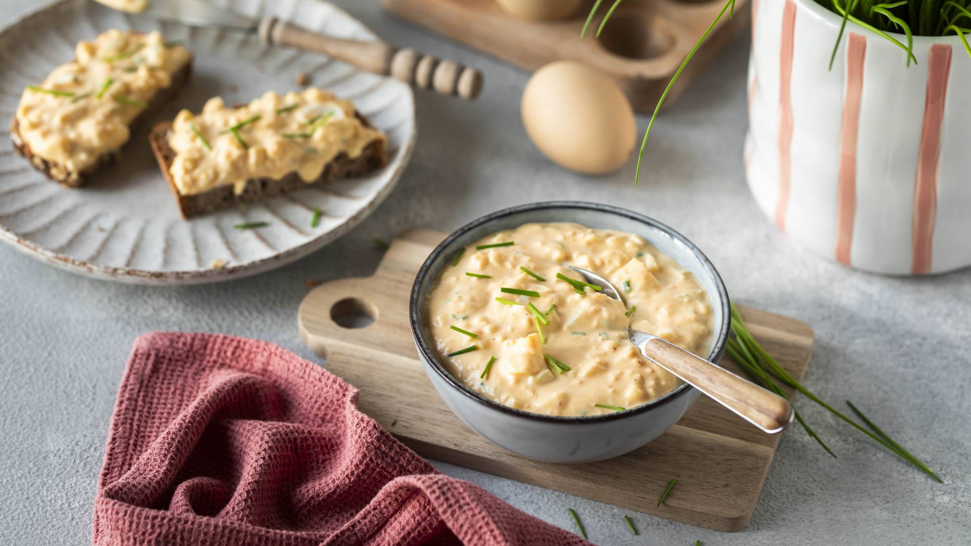 Eiersalat in einer Schale und auf Broten